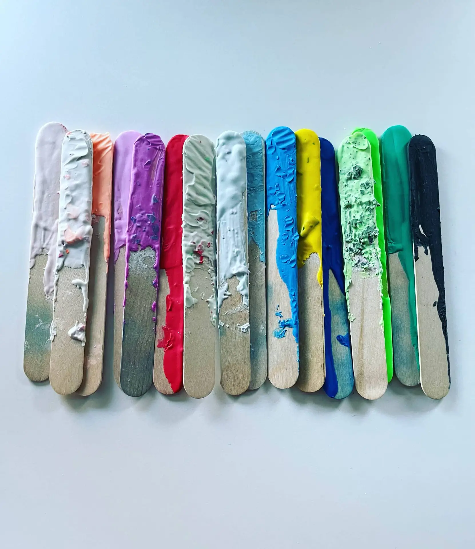Bunte Holzstäbchen mit Terrazzo-Farben aus Maikes Studio.Elise Workshop, nebeneinander auf weißer Fläche arrangiert.