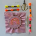 Stickset mit pinkem Stoff, Regenbogen-Design, bunten Garnen & Goldschere – für kreative Workshops im Studio.Elise.