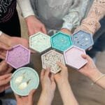 Kreativer Terrazzo Workshop bei Studio.Elise: Acht Hände halten bunte, selbstgemachte Tabletten mit Mustern und Schmuck.