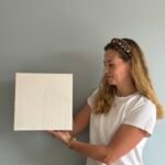 Maike im Studio.Elise hält ein strukturiertes weißes Kunstwerk – Inspiration für Terrazzo-, Makramee- und Textur-Workshops.