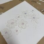 Strukturierte weiße Blumenmalerei mit rosa und lila Zentren auf Leinwand im Studio Elise, ideal für Maikes kreative Kunstworkshops.