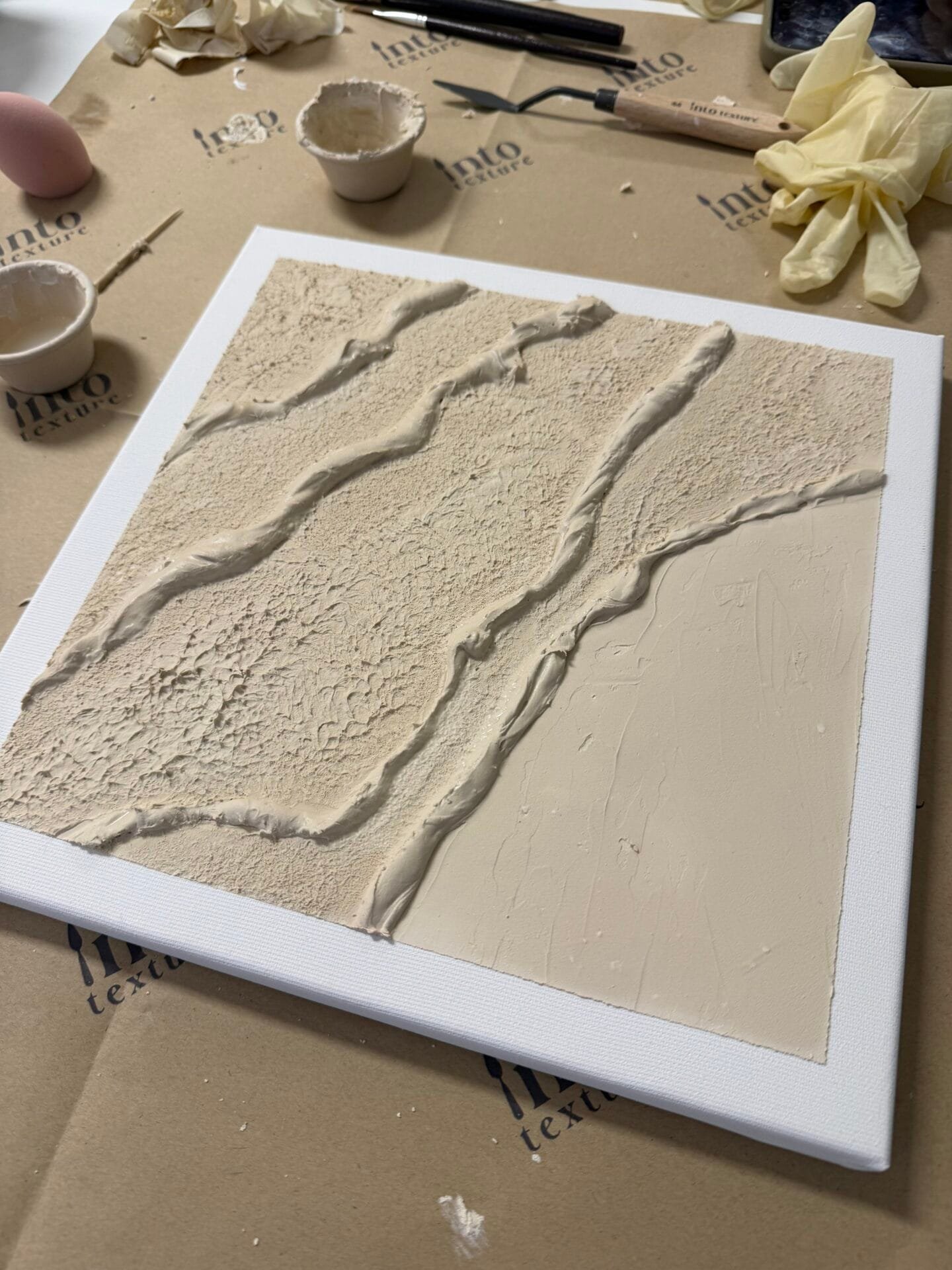 Strukturierte abstrakte beige Leinwand mit Terrazzo- und Makramee-Elementen, Workshop-Materialien im Studio Elise bei Maike.