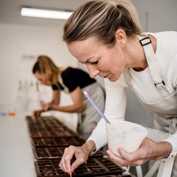 Maike leitet Workshop im Studio.Elise: Zwei Frauen fertigen Chocolaterie an, kreative Atmosphäre mit Magnetbuchstaben und hellem Design.
