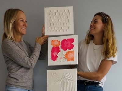 Maike und Teilnehmerin halten Terrazzo-Kunst aus Workshop im Studio Elise, mit Kreisen, Pink und Linien vor grauer Wand.
