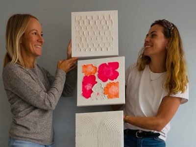 Maike und Teilnehmerin halten Terrazzo-Kunst aus Workshop im Studio Elise, mit Kreisen, Pink und Linien vor grauer Wand.